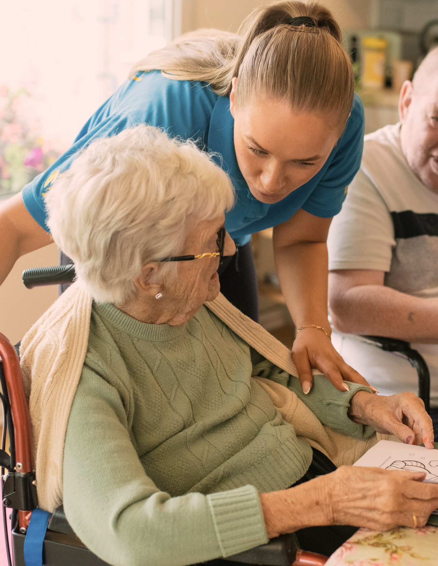 Caregiver assisting a senior woman with a coloring activity